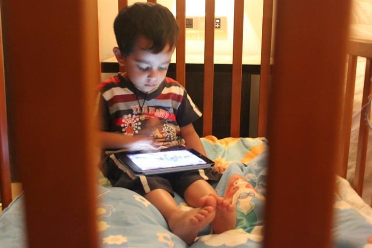 Kabirr Kohli as a small child, absorbed in a tablet